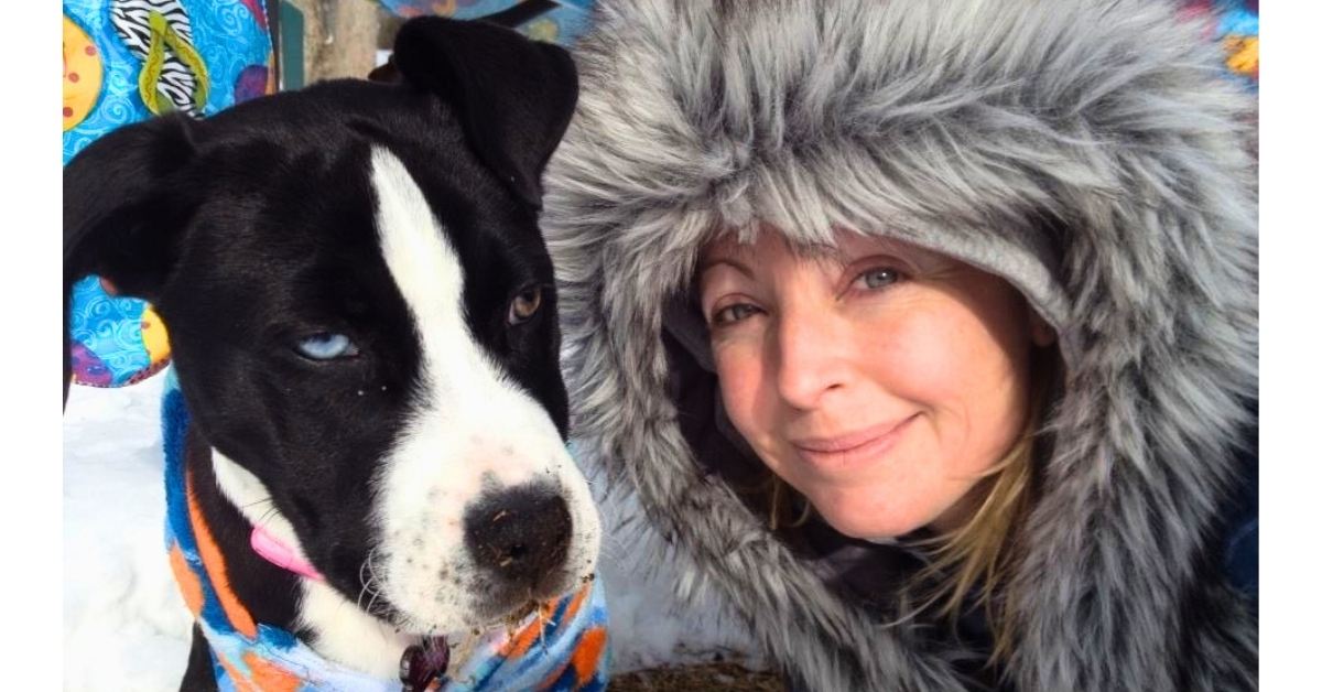 Woman and her rescue dog standing together in sunlight on a snowy day symbolizing trust, intuition, and choosing supportive relationships
